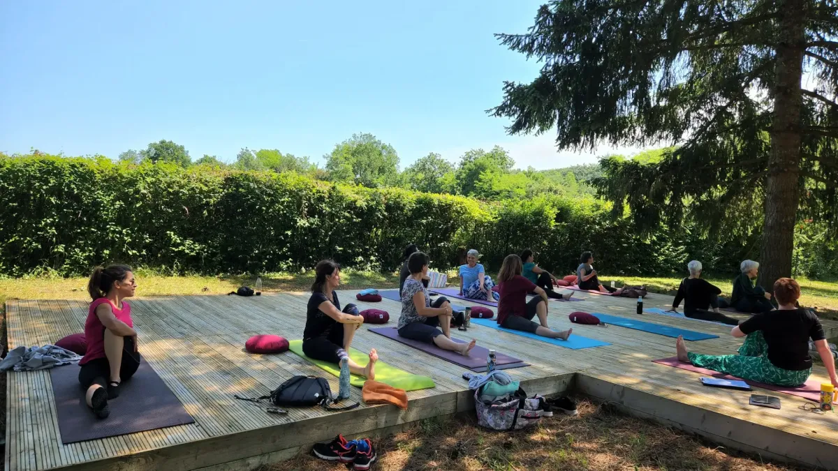 Pratique du yoga sur terrasse en bois ombragée sous les pins à Langoiran